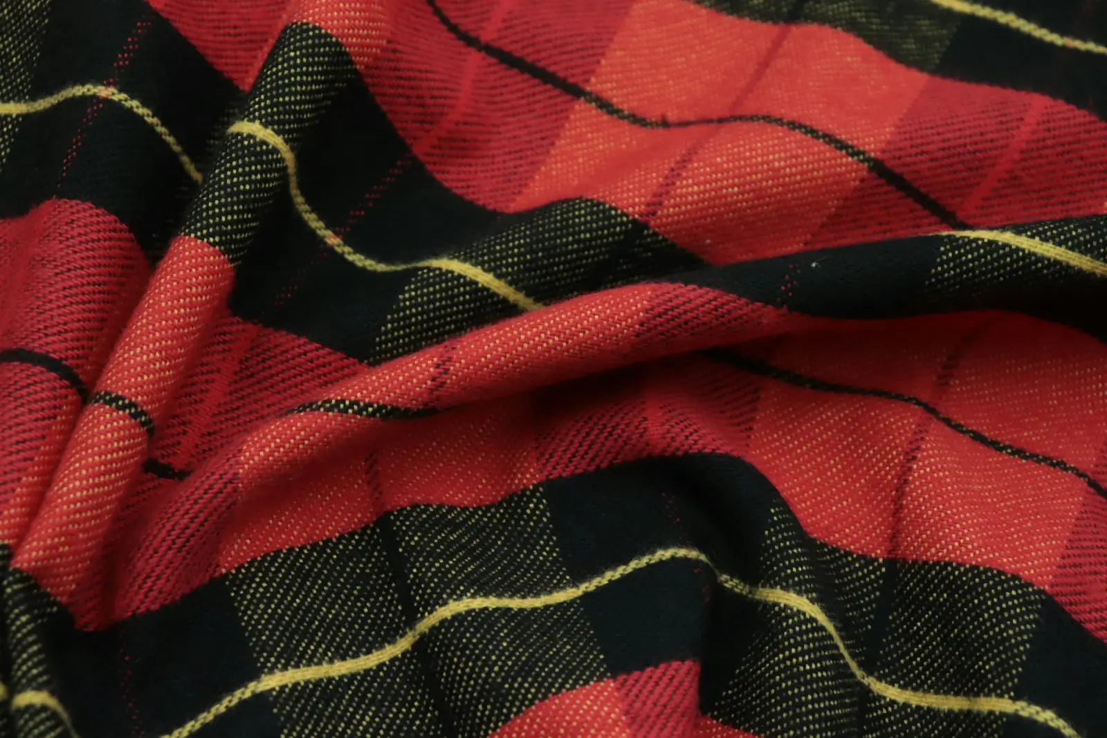 Close-up of a red and black plaid wool fabric with a thin yellow stripe