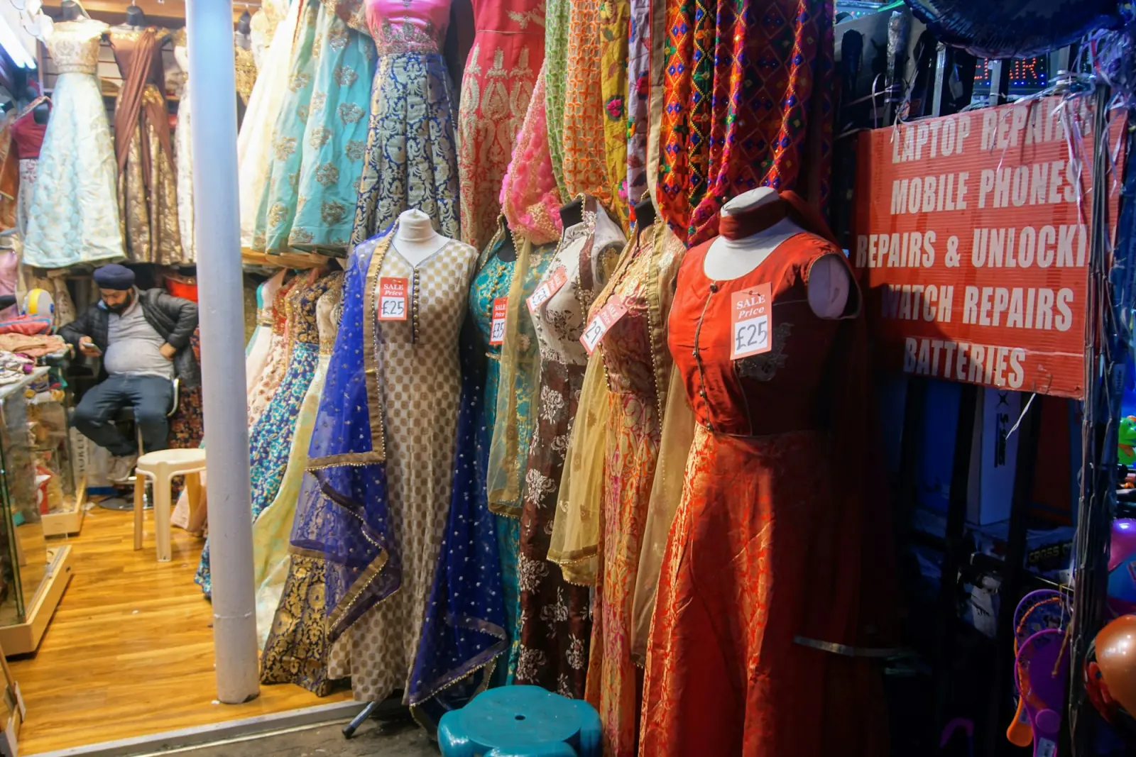 A shop front crowded with colourful lehengas, anarkali suits and dupattas on mannequins and hangers