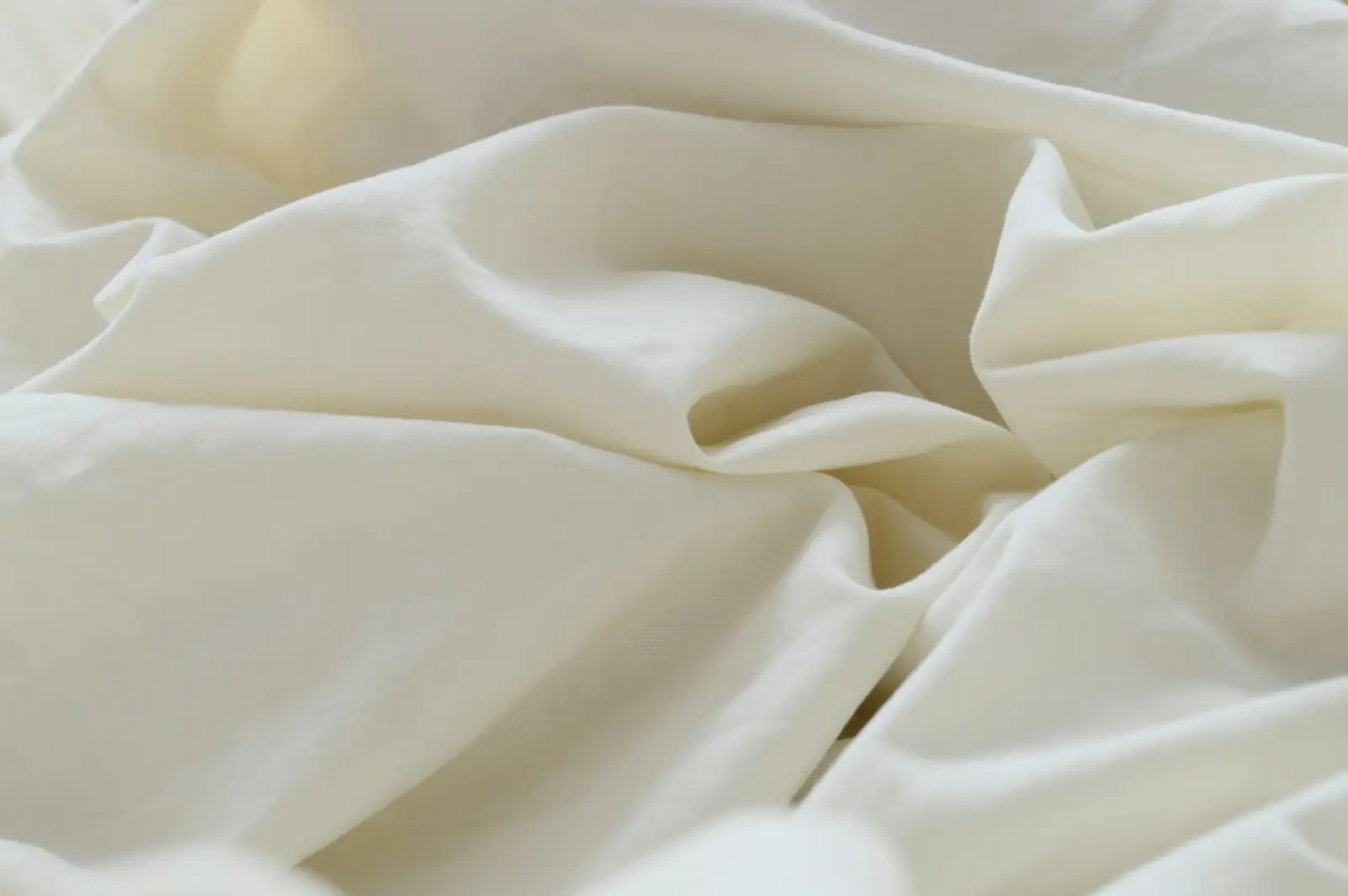 Soft folds of cream-coloured cotton muslin fabric lying loosely on a table