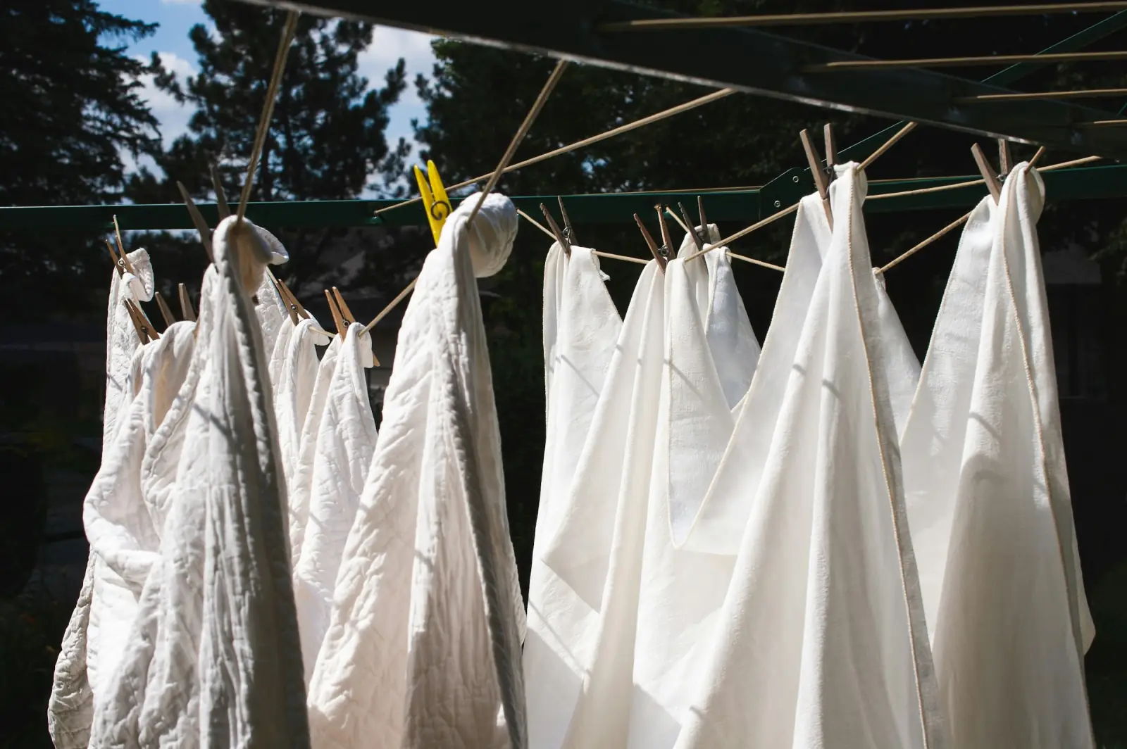 White cotton cloths hanging from pegs on an outdoor washing line in sunlight