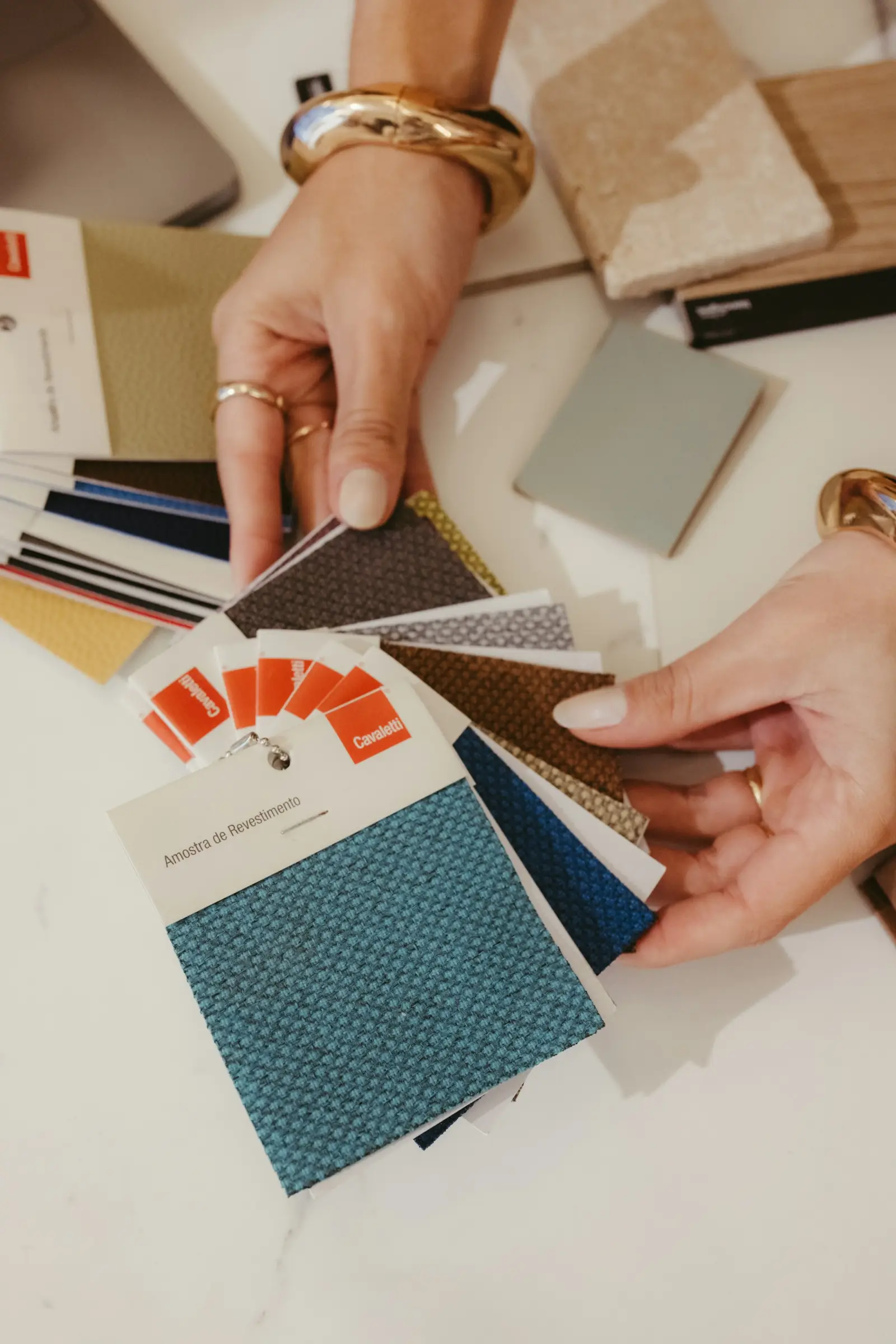 Hands flipping through a fan of fabric swatch cards in blues, greys and neutral textures
