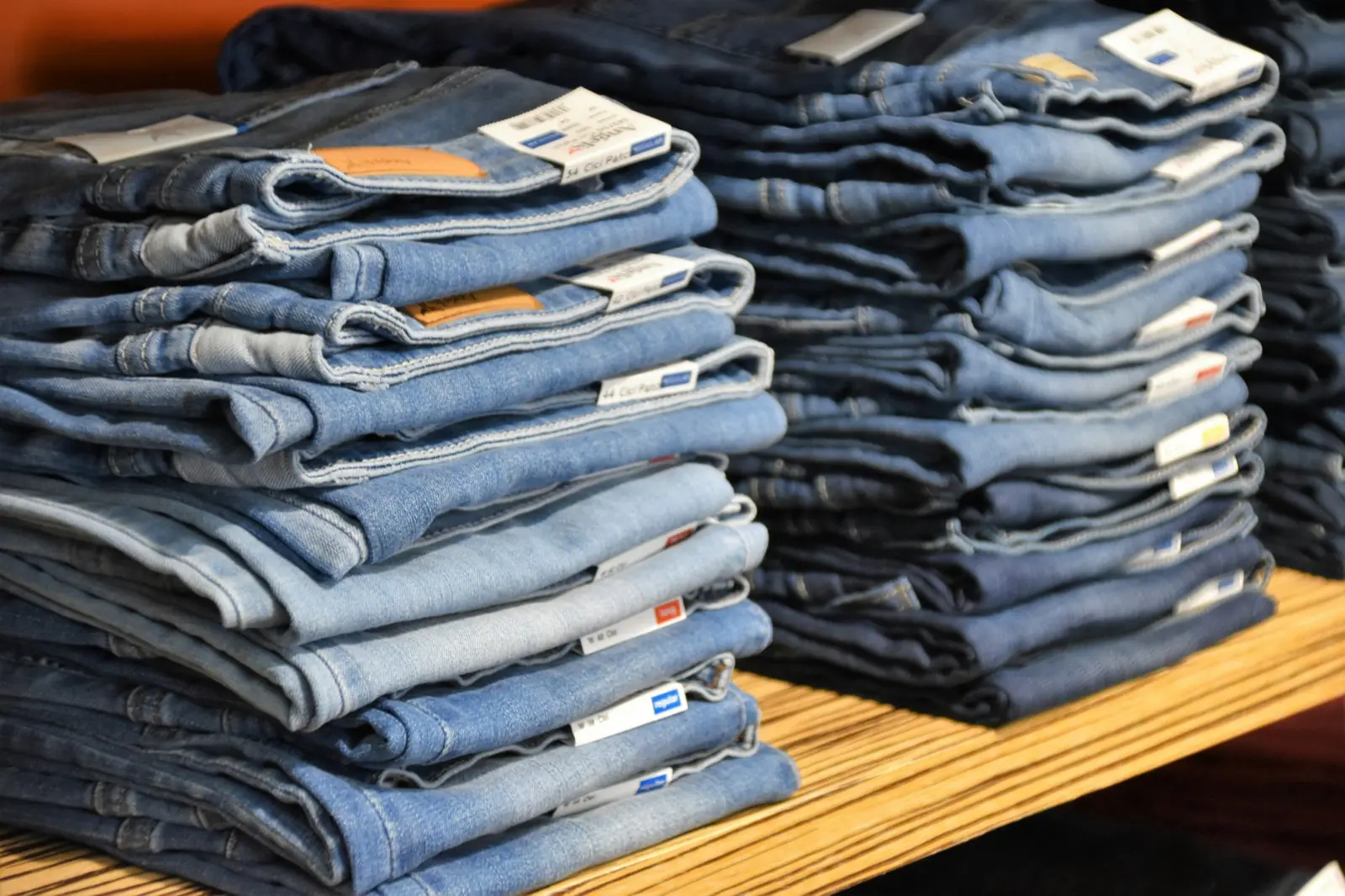 Stacks of folded blue denim jeans on a shop shelf