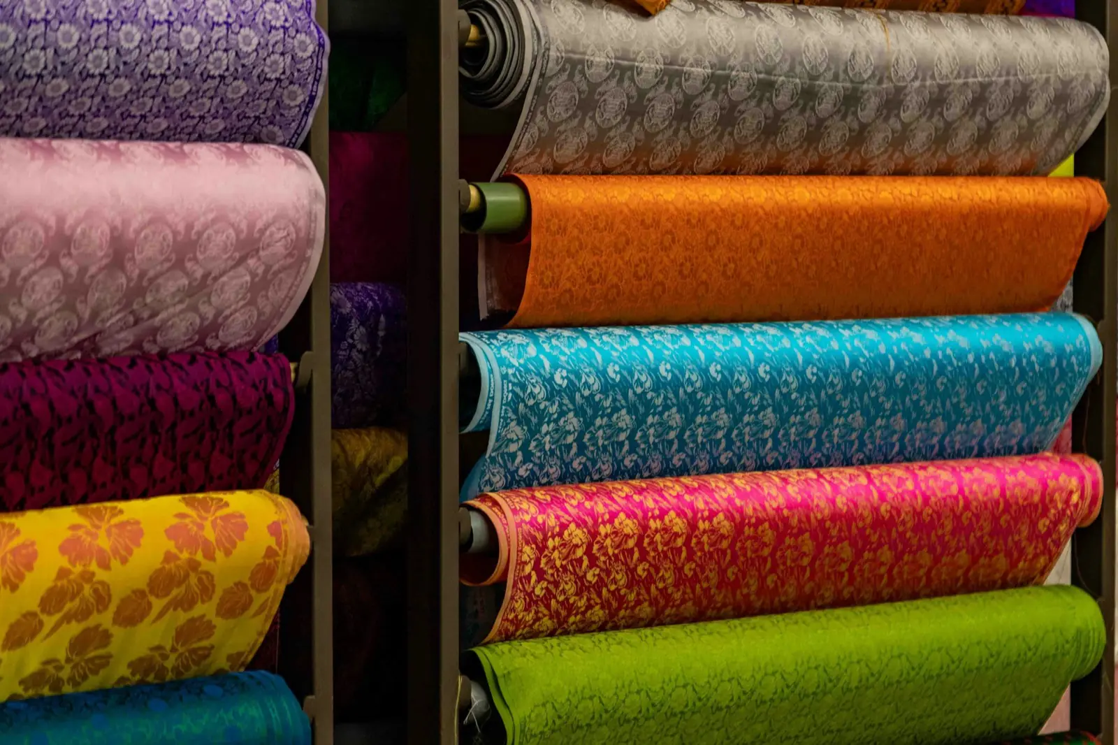Rolls of colourful patterned fabric stacked on shop shelves