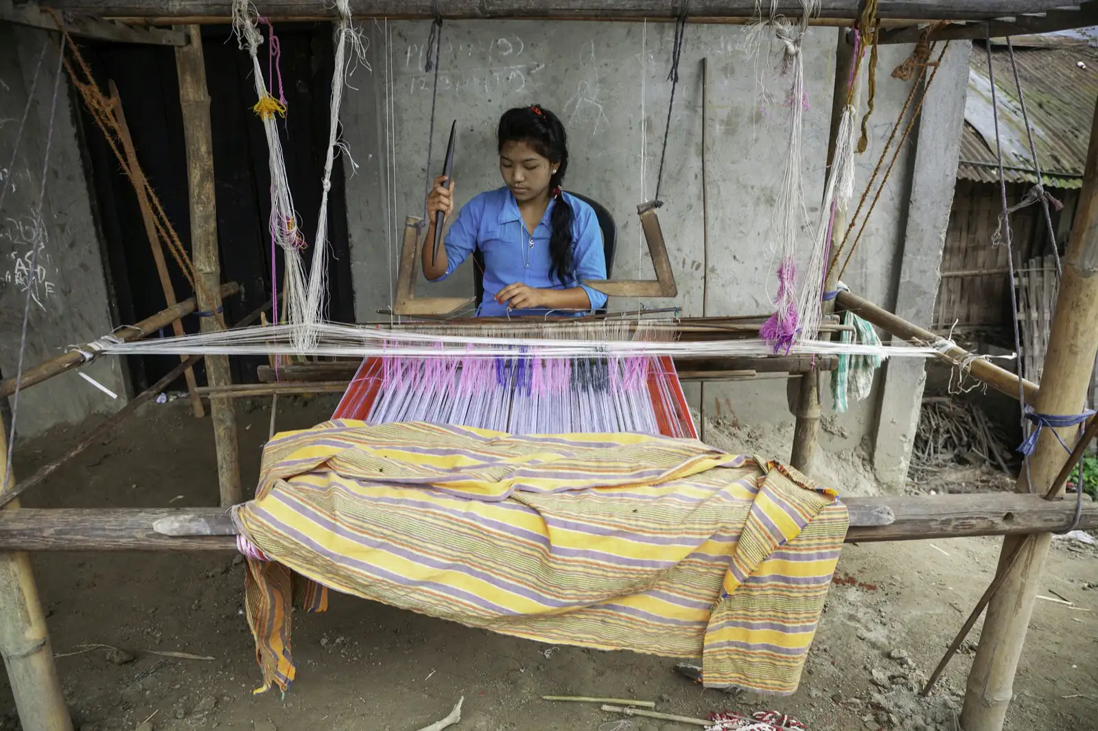 A woman weaving striped fabric on a traditional handloom