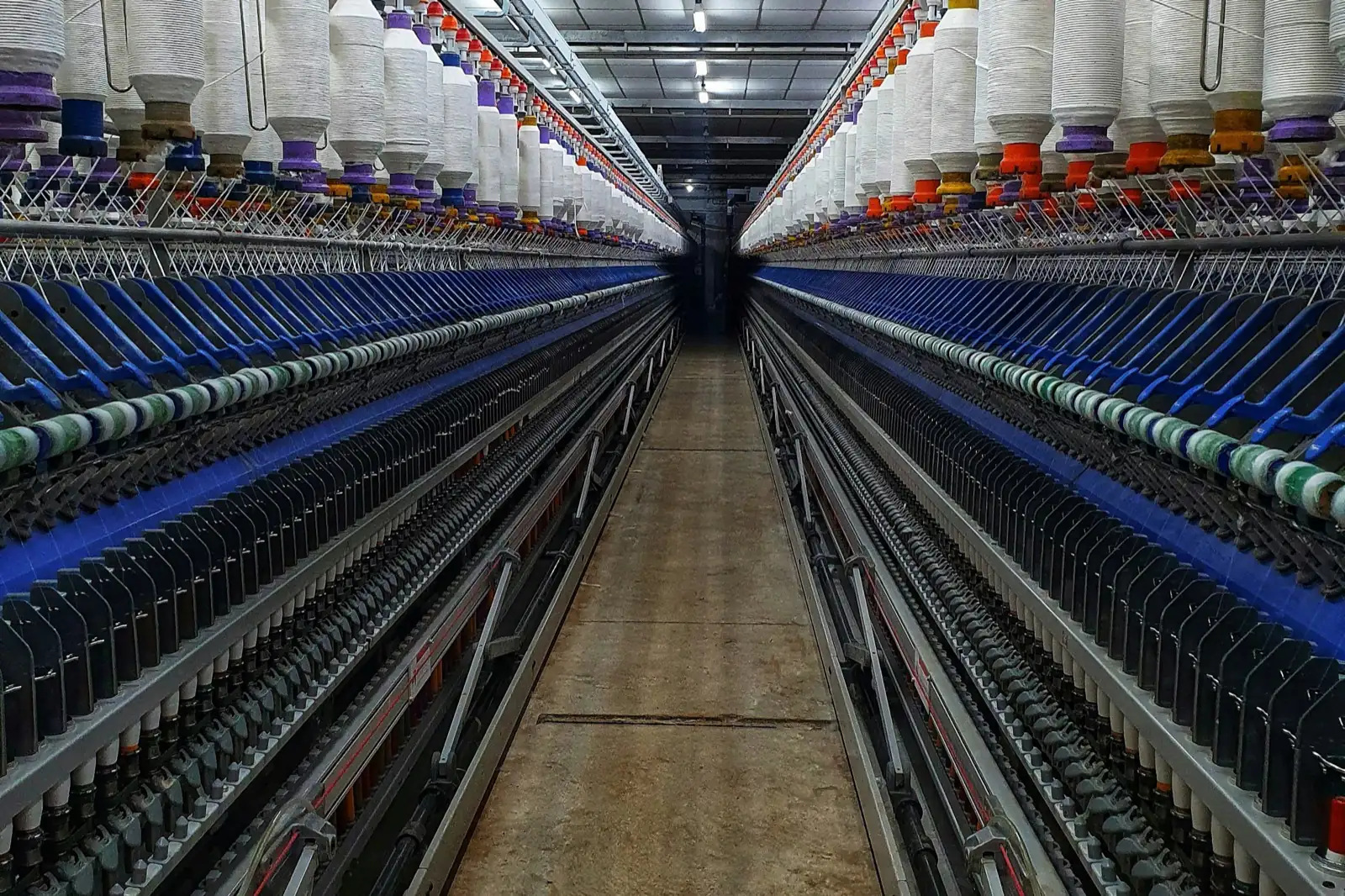Long rows of ring-spinning frames with yarn bobbins in an Indian spinning mill