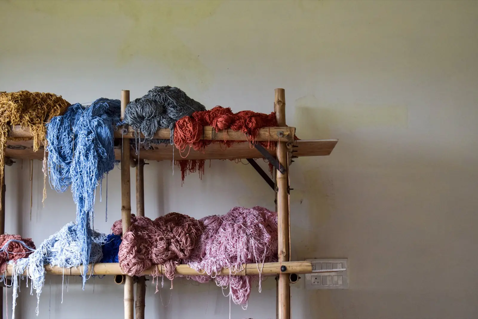 Hanks of dyed wool and yarn drying on a wooden rack