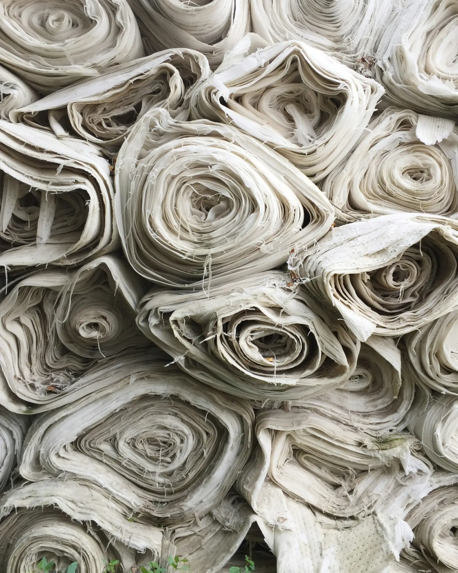 A heap of rolled grey and cream fabric pieces of different lengths piled together