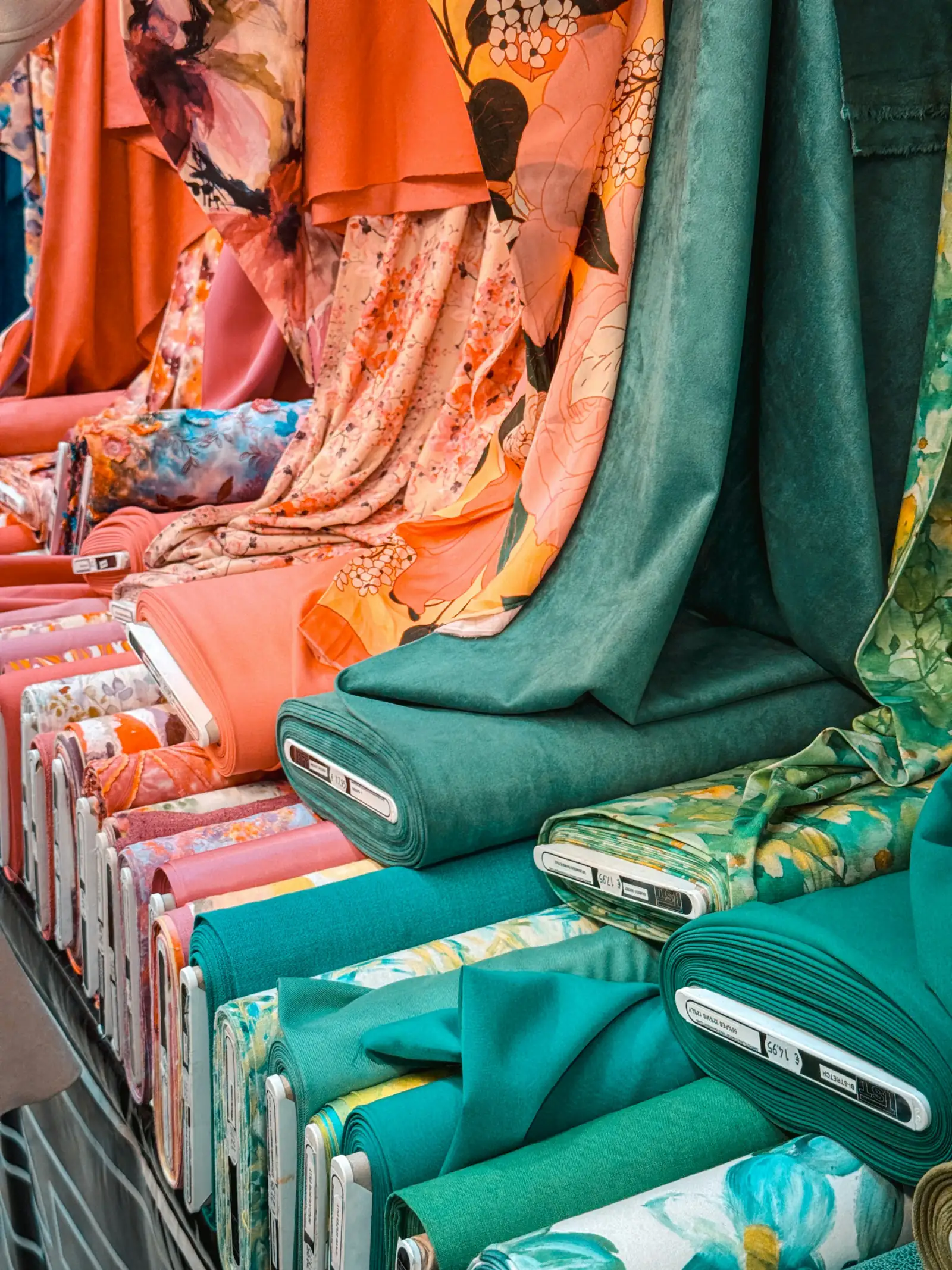 Rolls and folded lengths of bright printed and plain fabric displayed at a market stall