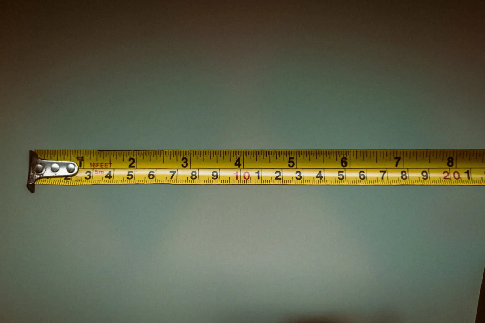 A hand holding a yellow retractable tape measure pulled out horizontally