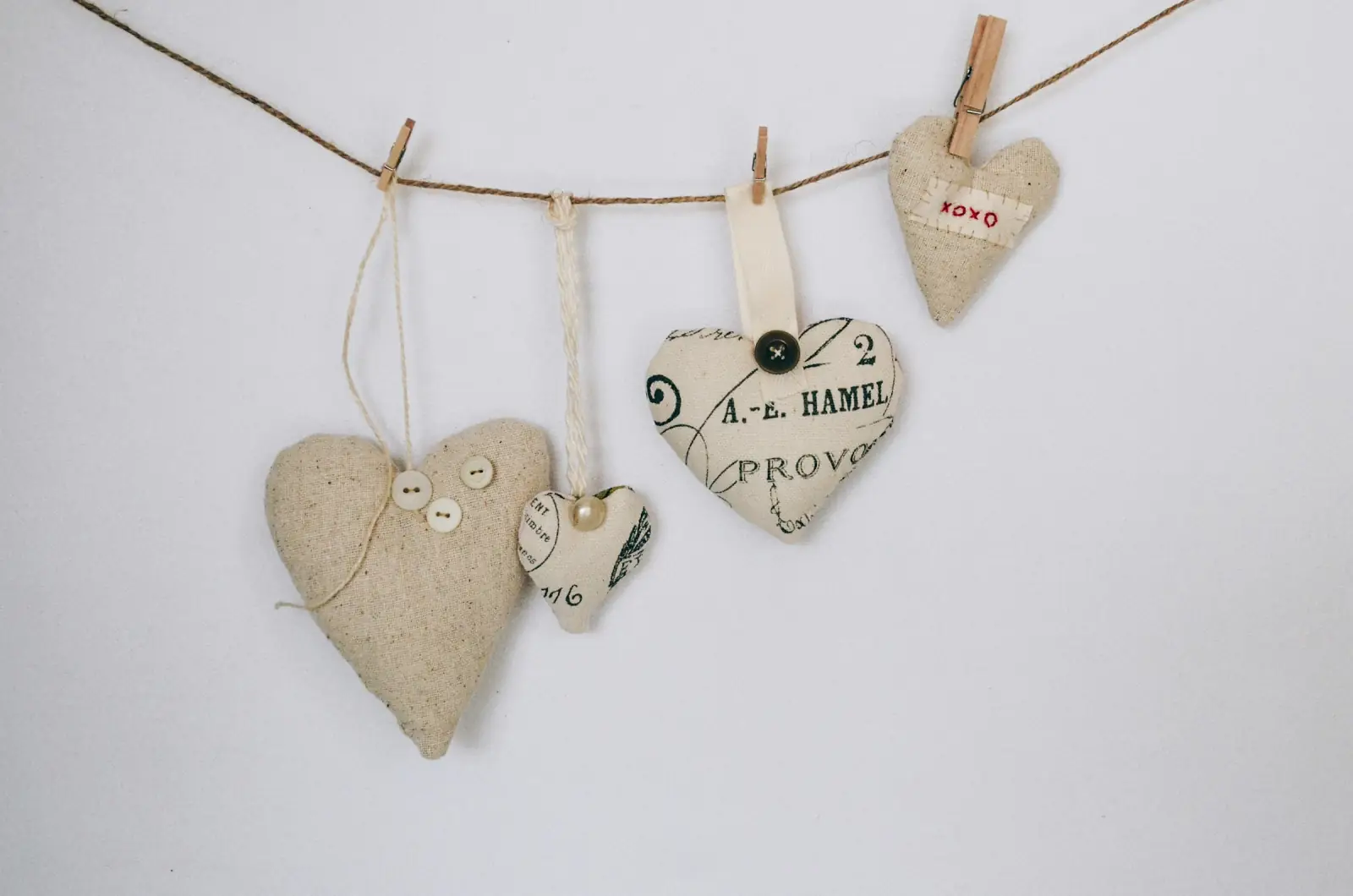 Handmade stuffed fabric hearts in natural linen and printed cotton hanging from a string with wooden pegs