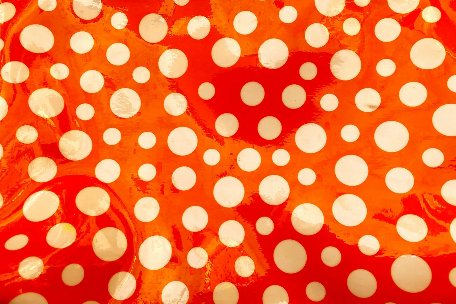 Red fabric printed with cream polka dots of varying sizes