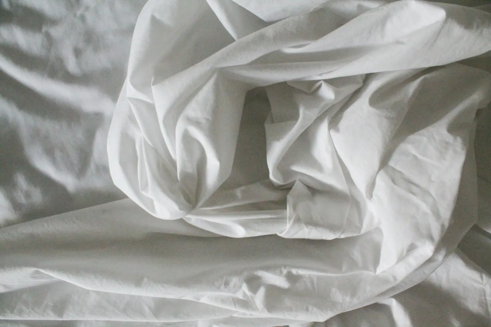Soft folds of plain white cotton sheeting lying loosely
